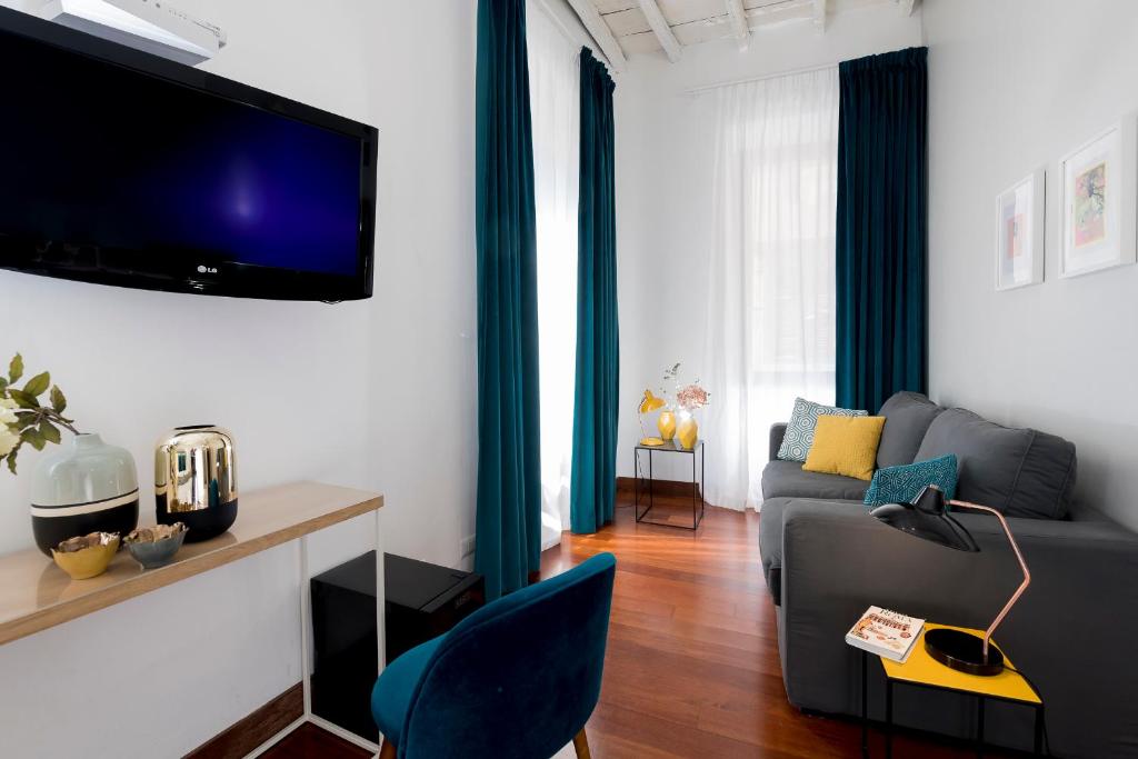 ein Wohnzimmer mit einem Sofa und einem TV an der Wand in der Unterkunft Maison Giulia in Rom