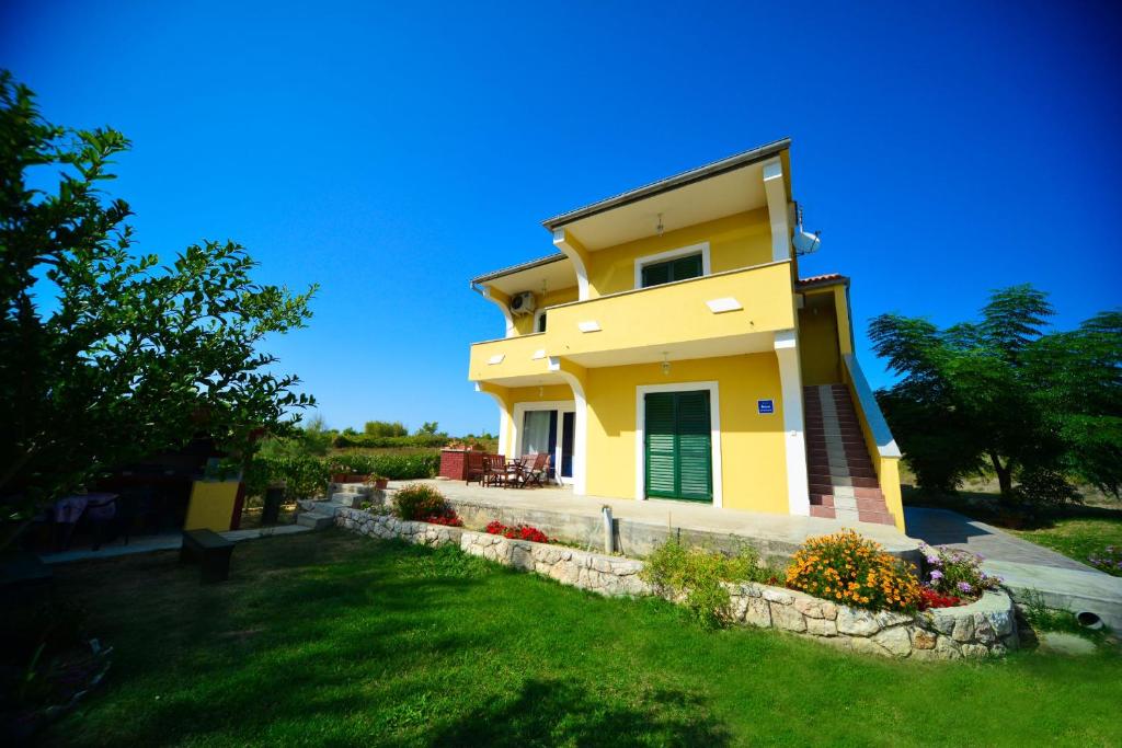 ein gelbes Haus mit grüner Tür und Hof in der Unterkunft Apartment Marcella 1 in Ljubač