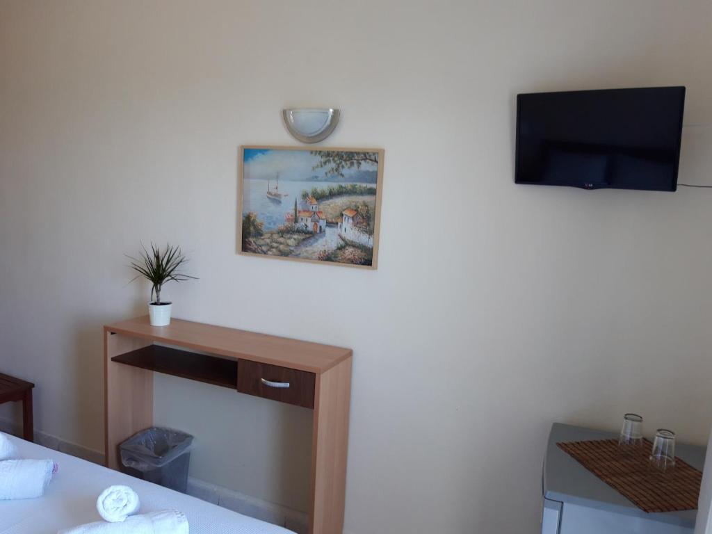 a room with a bed and a tv on a wall at Vourvourou Hotel in Vourvourou