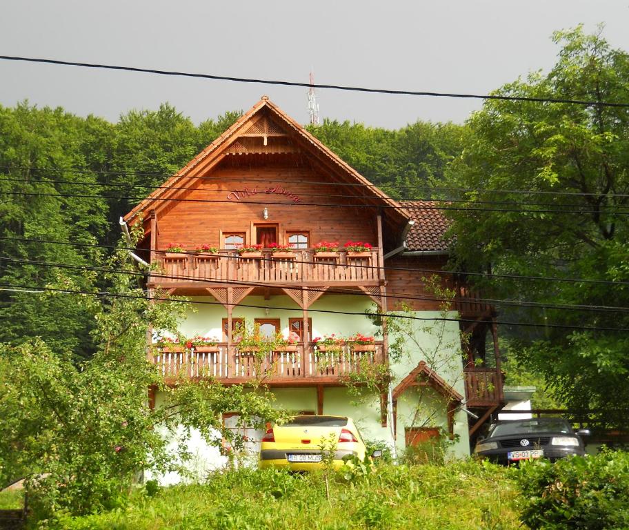 una casa de madera con balcón y coches delante de ella en Vila Anna, en Sovata