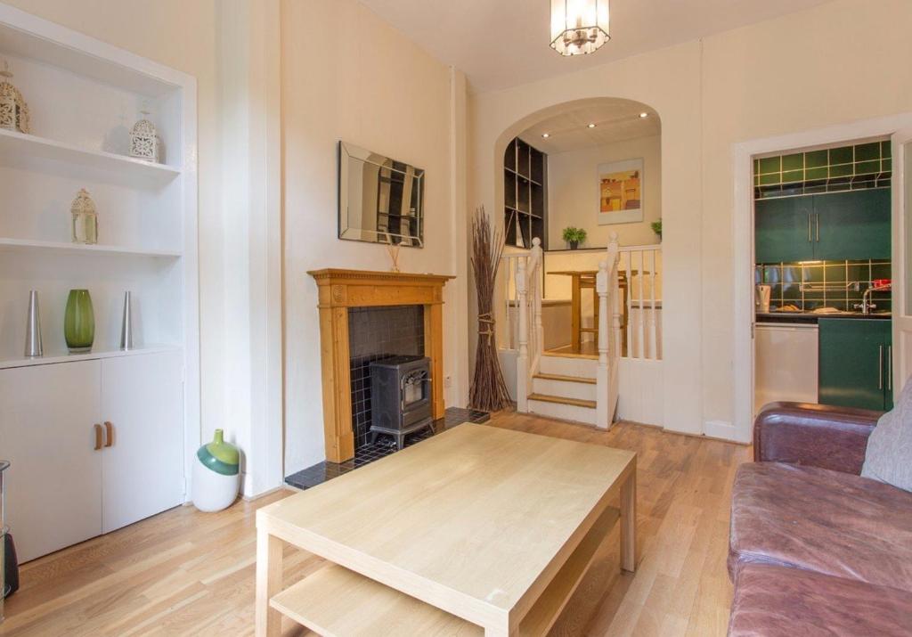 uma sala de estar com uma mesa e uma lareira em The Broughton Road Residence em Edimburgo