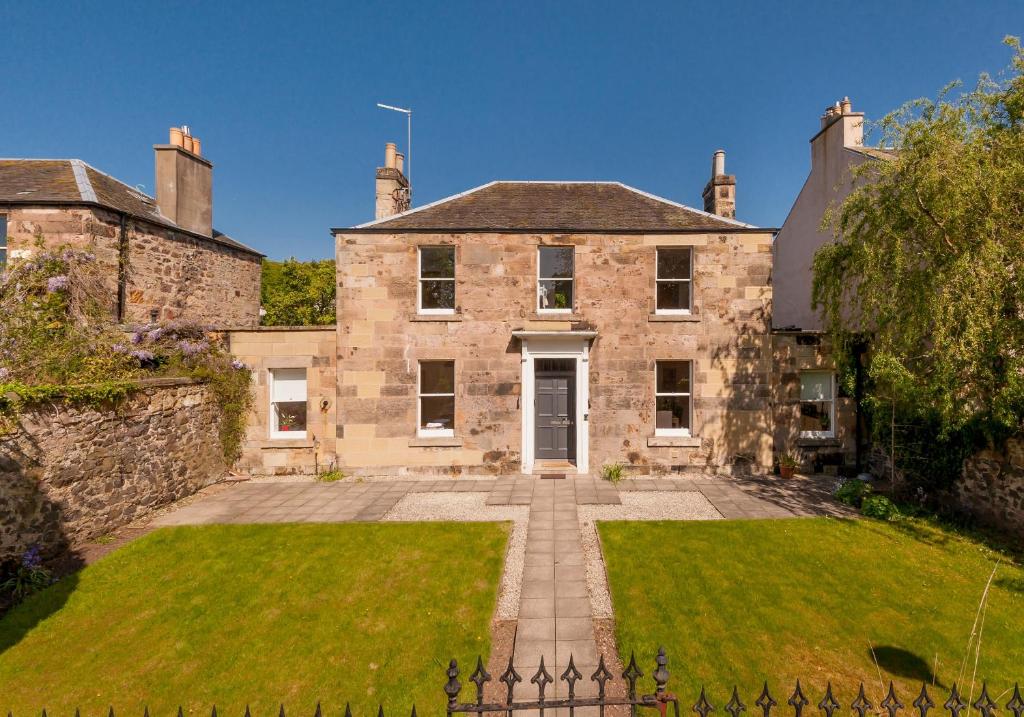 una antigua casa de piedra con un gran patio en The Lochside House Residence en Edimburgo