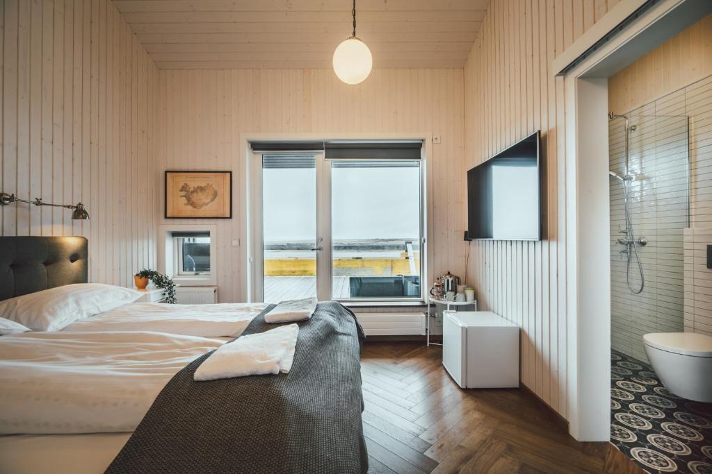 1 dormitorio con cama, bañera y TV en Ekra Glacier Lagoon, en Gerdi