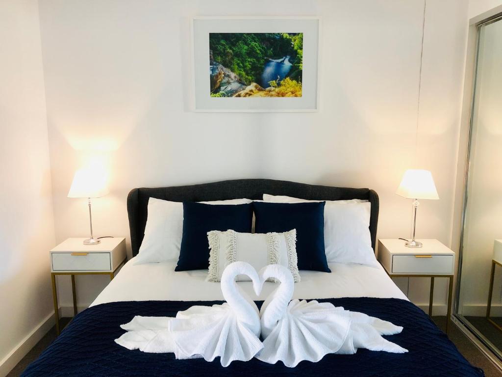 dos cisnes blancos están sentados en una cama en Central Escape @ Adelaide CBD en Adelaida