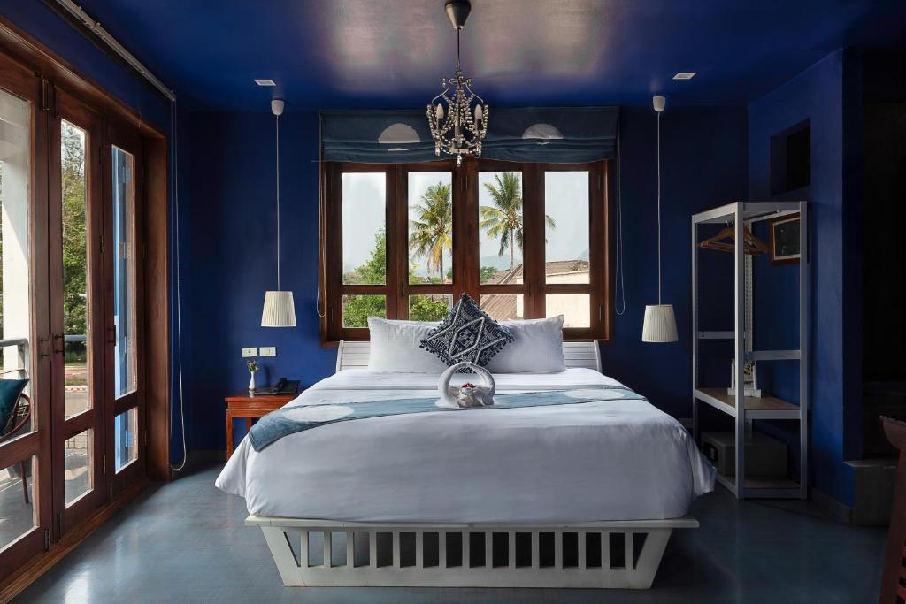 a blue bedroom with a bed and a window at Indigo House Hotel in Luang Prabang