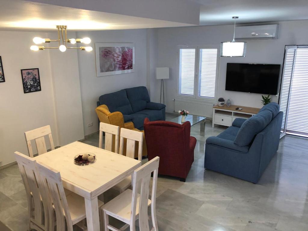 een woonkamer met een tafel en stoelen en een televisie bij La Casa de Las Flores in Mairena del Aljarafe