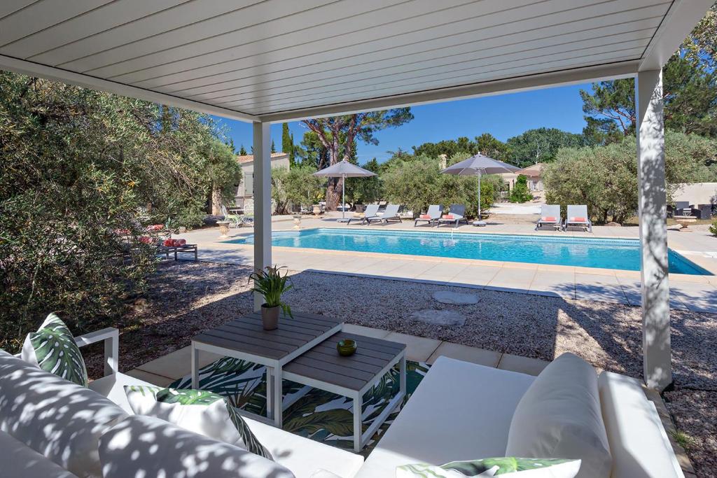 un patio con una mesa y una piscina en La Méridienne, en Mouriès