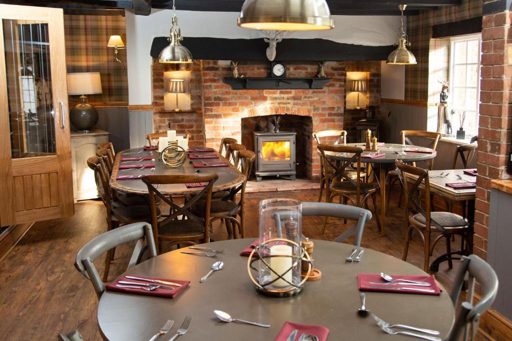 Crown Inn في Marston Montgomery: غرفة طعام مع طاولات ومدفأة