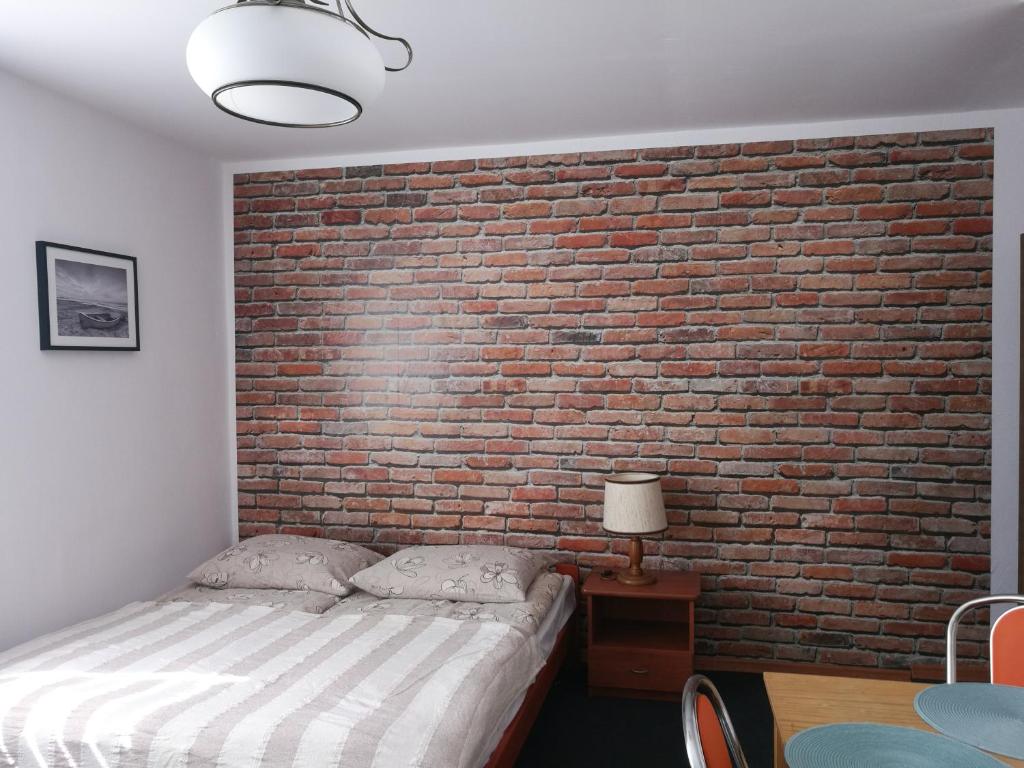 a bedroom with a brick wall and a bed at Ośrodek Wczasowy Daga in Dziwnów