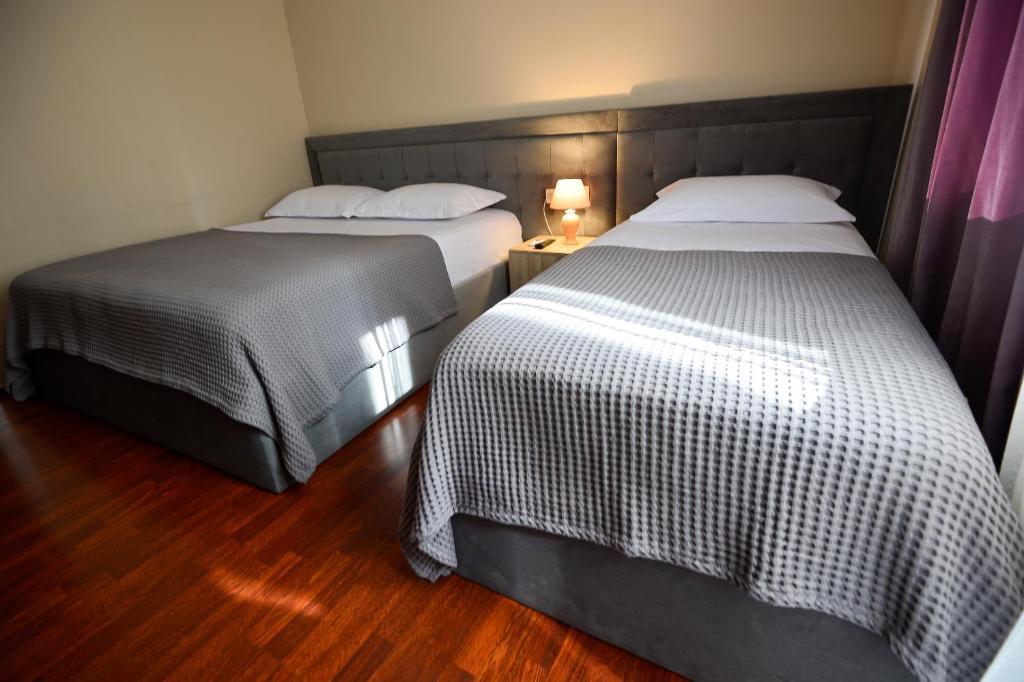 two beds in a room with wooden floors at Hotel Niku in Tirana