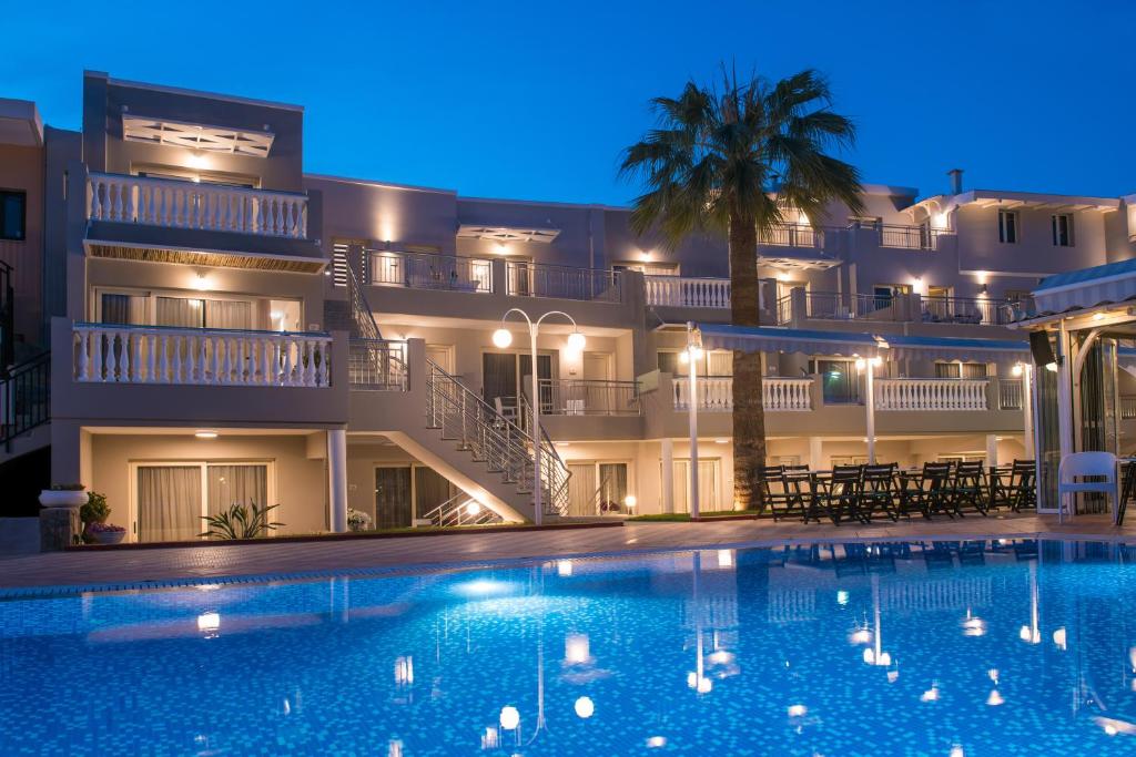 a large swimming pool in front of a building at night at Sarpidon Apartments in Malia