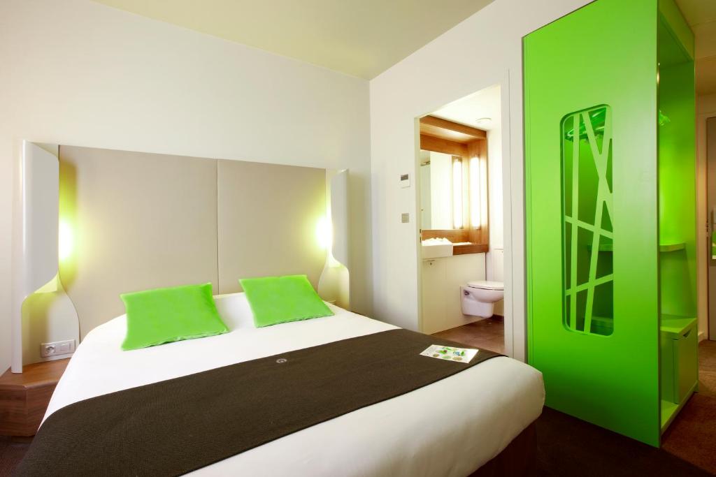 a bedroom with a large bed with green accents at Campanile Carcassonne Est - La Cité in Carcassonne