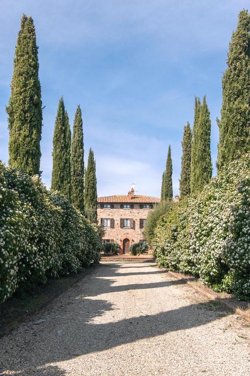a large building with trees in front of a driveway at Villa Chiccheio Rooms in Montepulciano