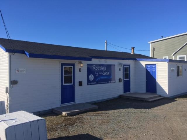 a white building with a blue sign on it at Robbins by the Sea in Bonavista