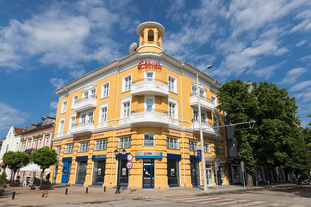 un edificio amarillo con una torre encima en Hotel Central en Ruse