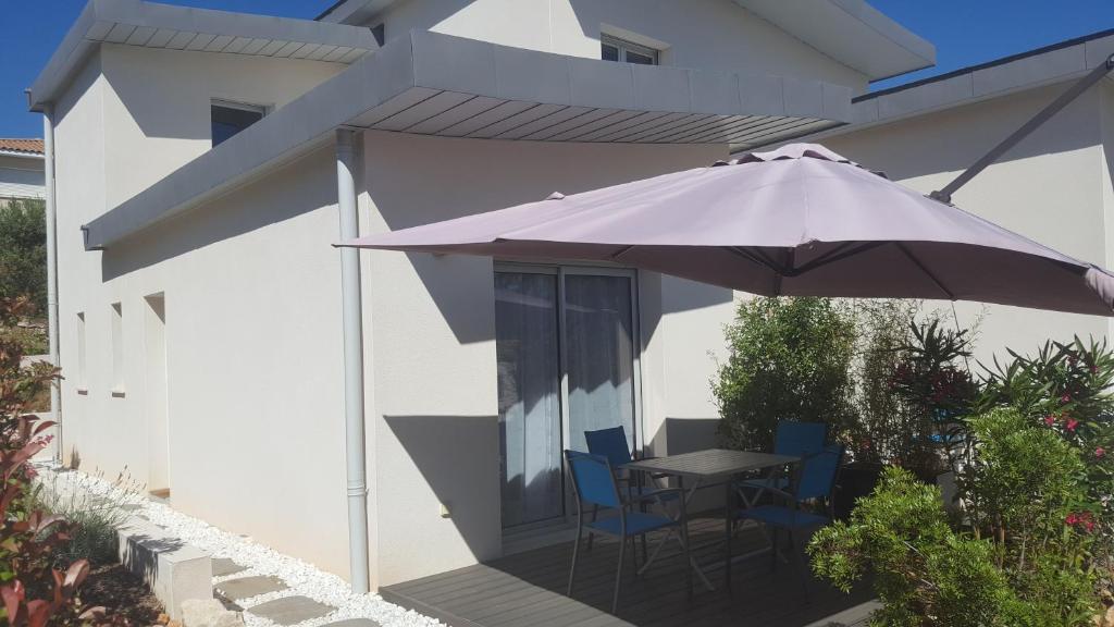 a table and chairs under an umbrella on a patio at FEIJOA in Saint-Gély-du-Fesc