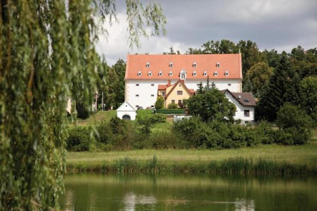 ein großes weißes Gebäude mit rotem Dach neben einem See in der Unterkunft Schüttkasten Geras in Geras