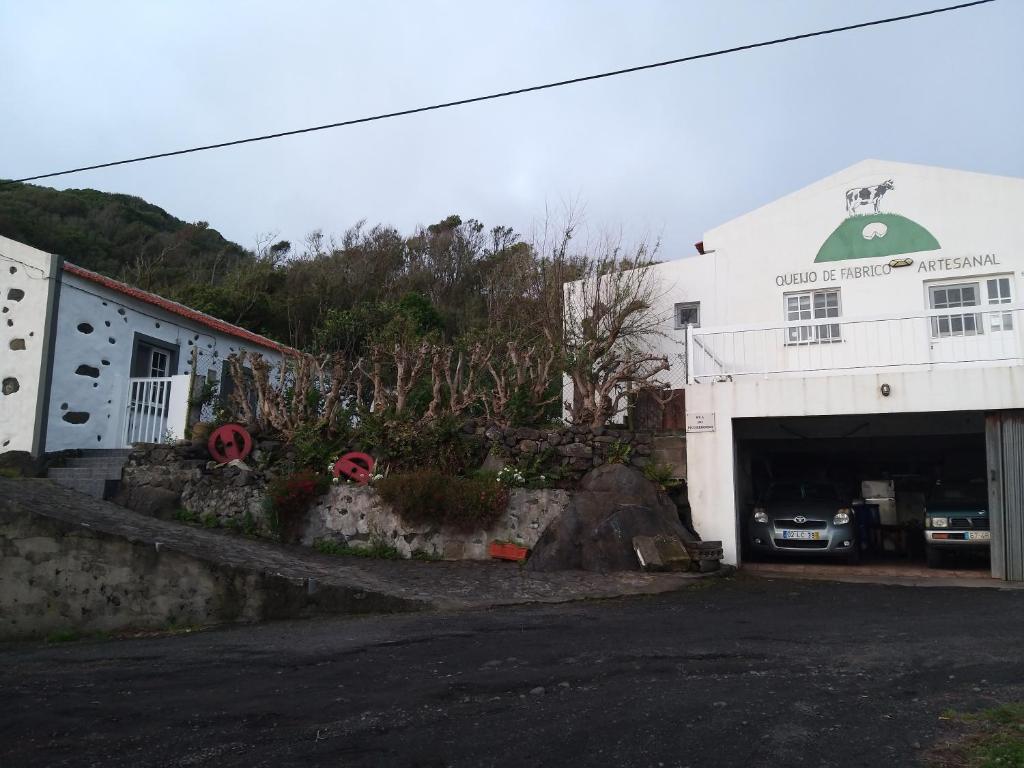 un edificio blanco con un aparcamiento con garaje en Casa da Queijaria en Faja Grande