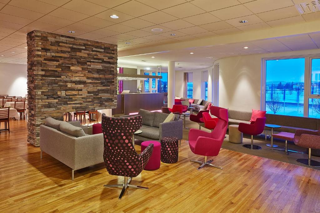a lobby with couches and chairs and a brick wall at Hérað - Berjaya Iceland Hotels in Egilsstaðir