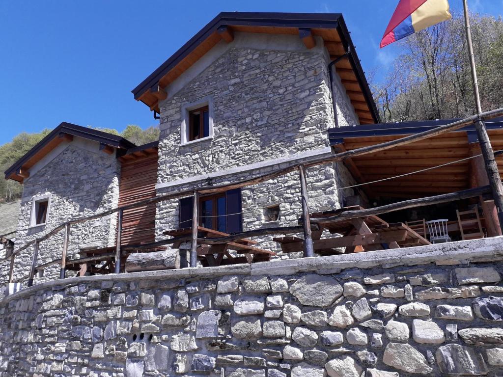 a stone house with a flag on a stone wall at Le Casette di Laila in Colonno