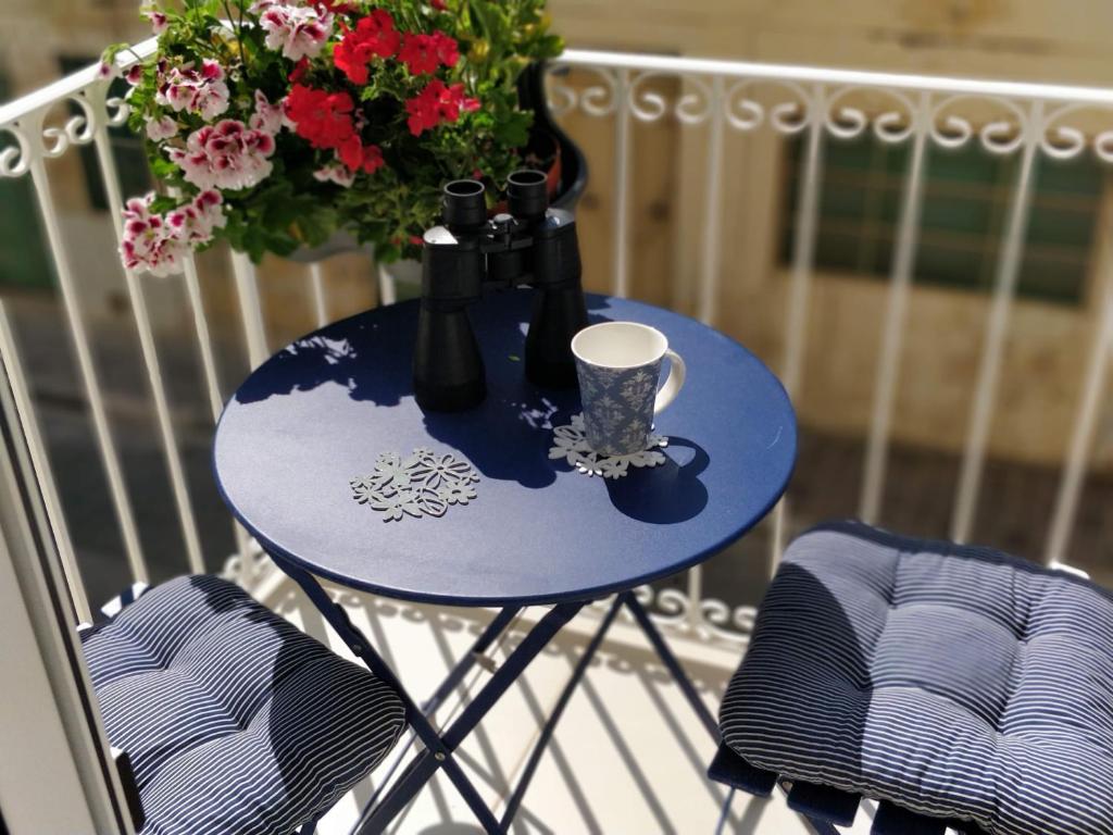 a blue table with vases and a cup on a balcony at Little Blue House in Marsalforn