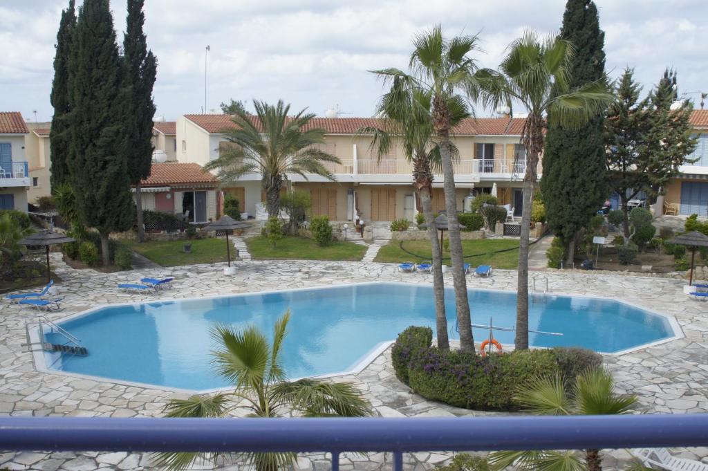 a swimming pool with palm trees in front of a building at Family Paradise- luxury combined with home comfort in Paphos City