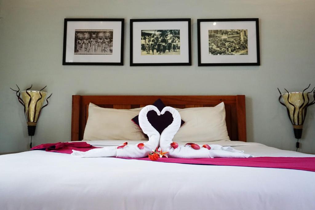 una cama con dos animales de peluche en forma de corazón en Louto Dmell Guesthouse, en Sanur