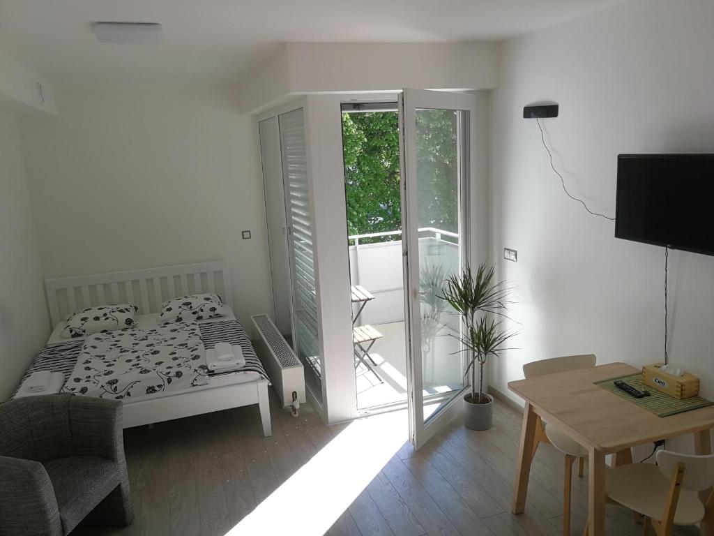 a white bedroom with a bed and a balcony at Alfa Riverside Brno in Brno