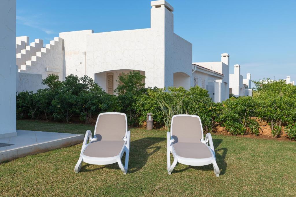 two chairs sitting on the grass in front of a building at Blue Sea Villas by Wonderful Italy in Ostuni