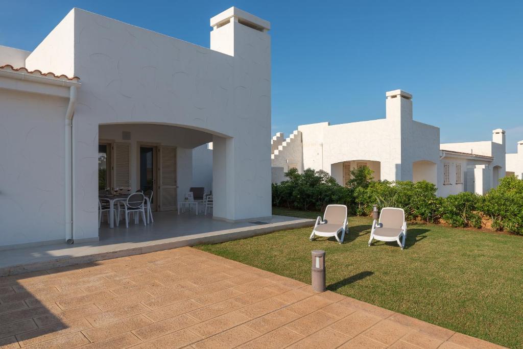 a white house with two lawn chairs in the yard at Blue Sea Villas by Wonderful Italy in Ostuni
