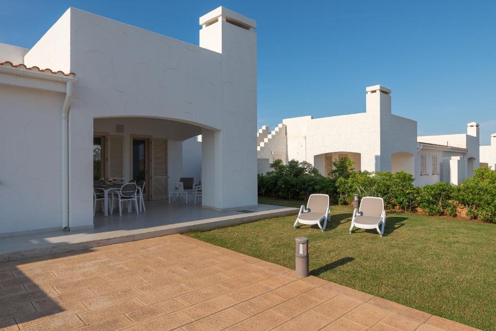 une maison blanche avec 2 chaises longues dans la cour dans l'établissement Blue Sea Villas by Wonderful Italy, à Ostuni