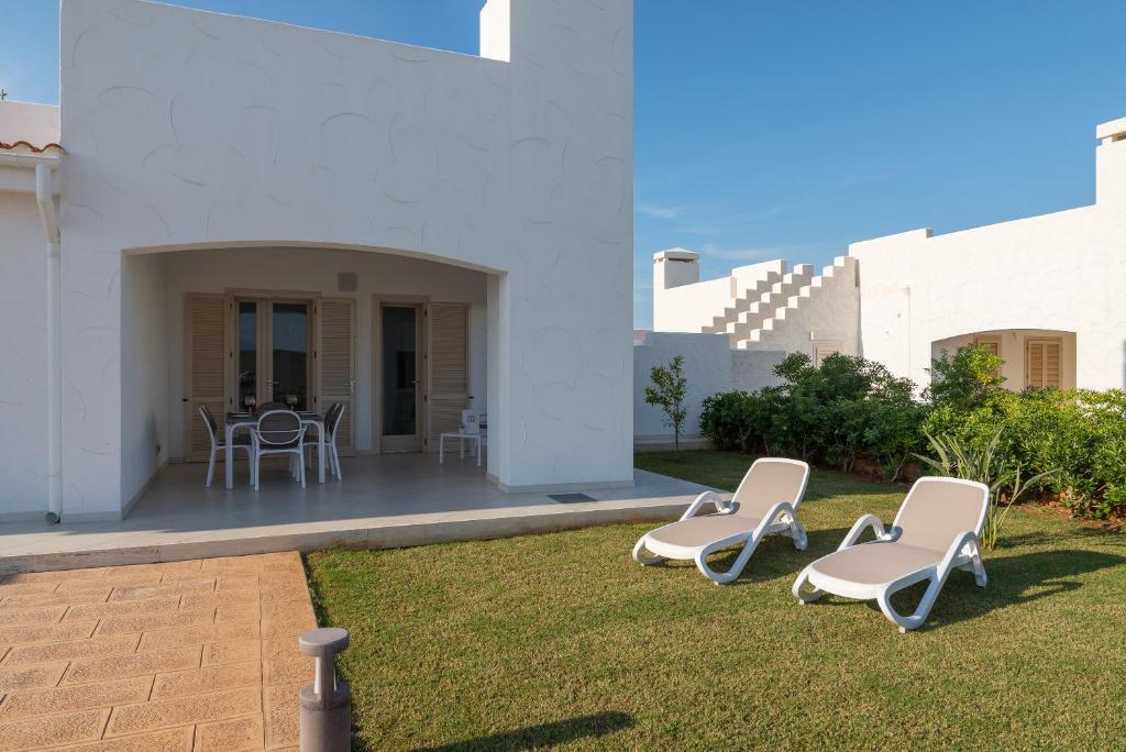 a group of chairs sitting on the grass in a yard at Blue Sea Villas by Wonderful Italy in Ostuni