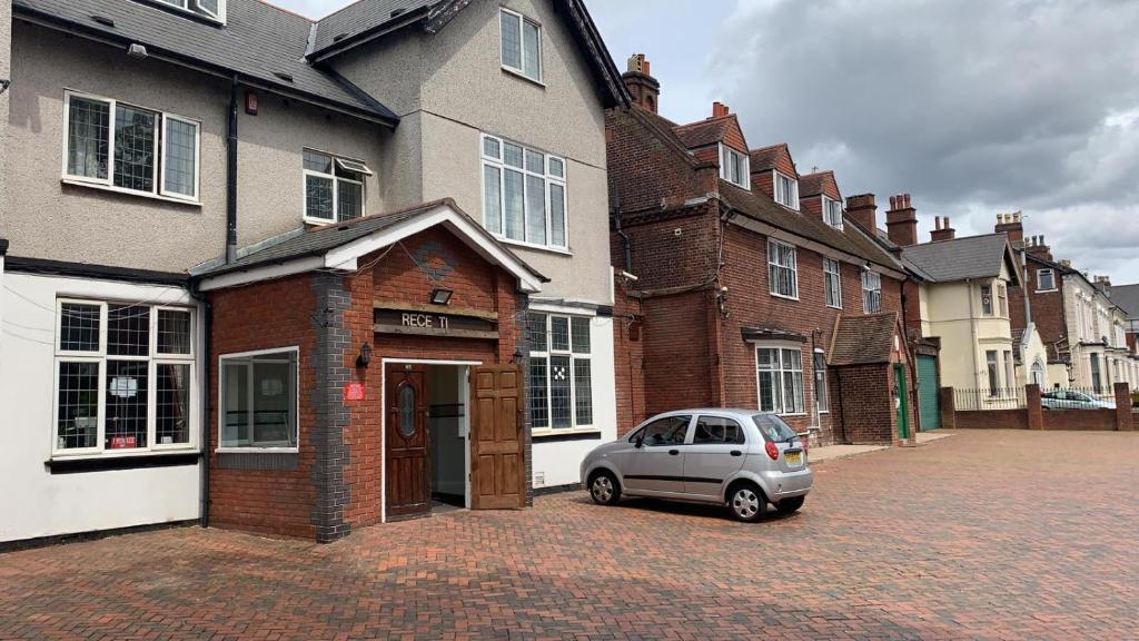 una piccola auto parcheggiata di fronte a un edificio di mattoni di Hagley Hotel a Birmingham