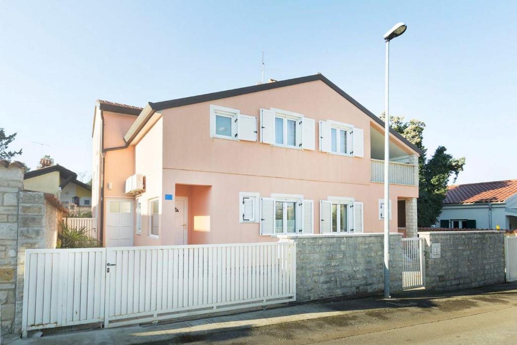 a pink house with a white fence at Put Maslina 7 in Savudrija