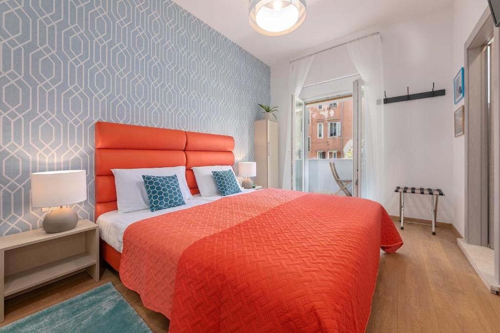 a bedroom with a large bed with an orange bedspread at La Preziosa Rooms in Pula