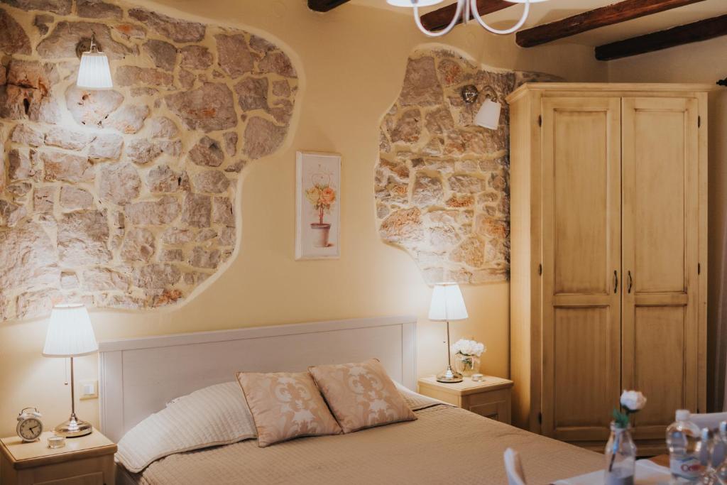 a bedroom with a bed and a stone wall at Rooms Villa Duketis in Rovinj