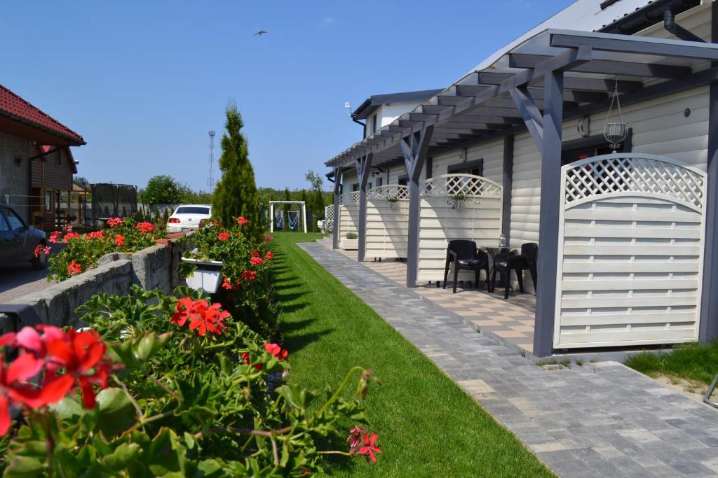 a backyard with a white pergola and red flowers at Apartamenty Lawenda in Wrzosowo