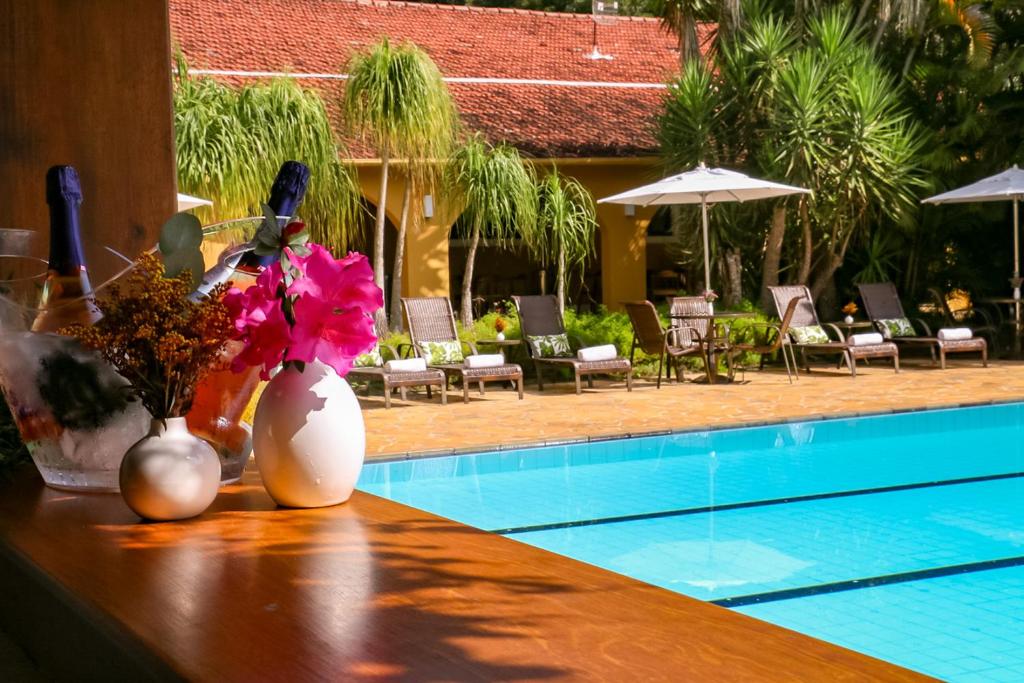 uma mesa com flores ao lado de uma piscina em Hotel Capim Limão Itaipava em Itaipava