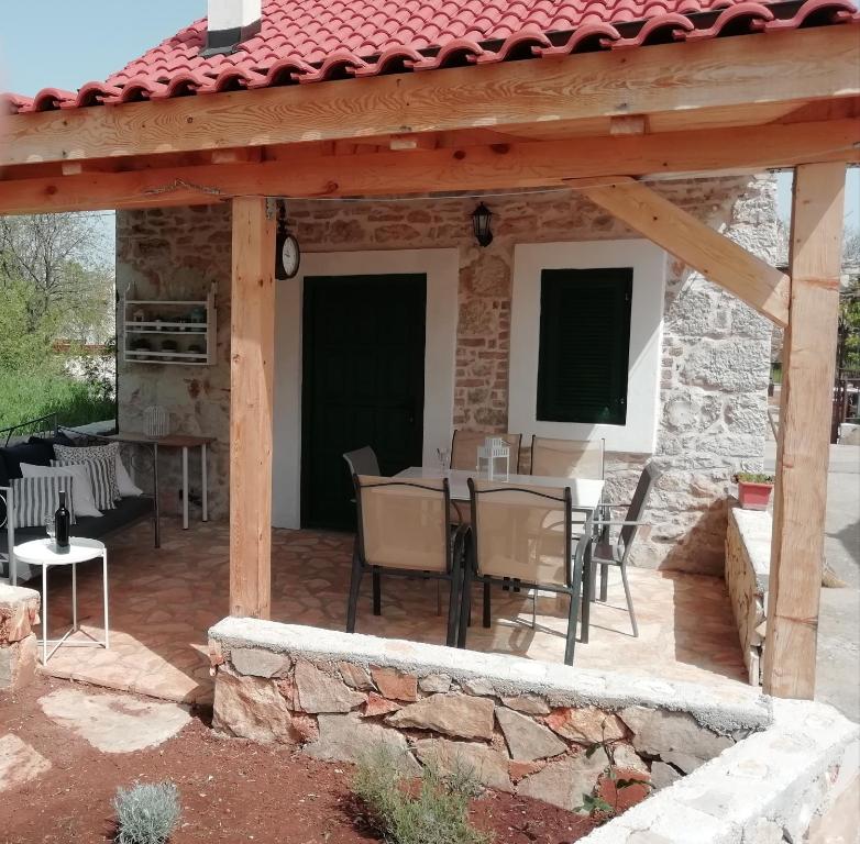 a patio with a table and chairs under a wooden pergola at Krka Waterfalls Stonehouse Roko in Lozovac
