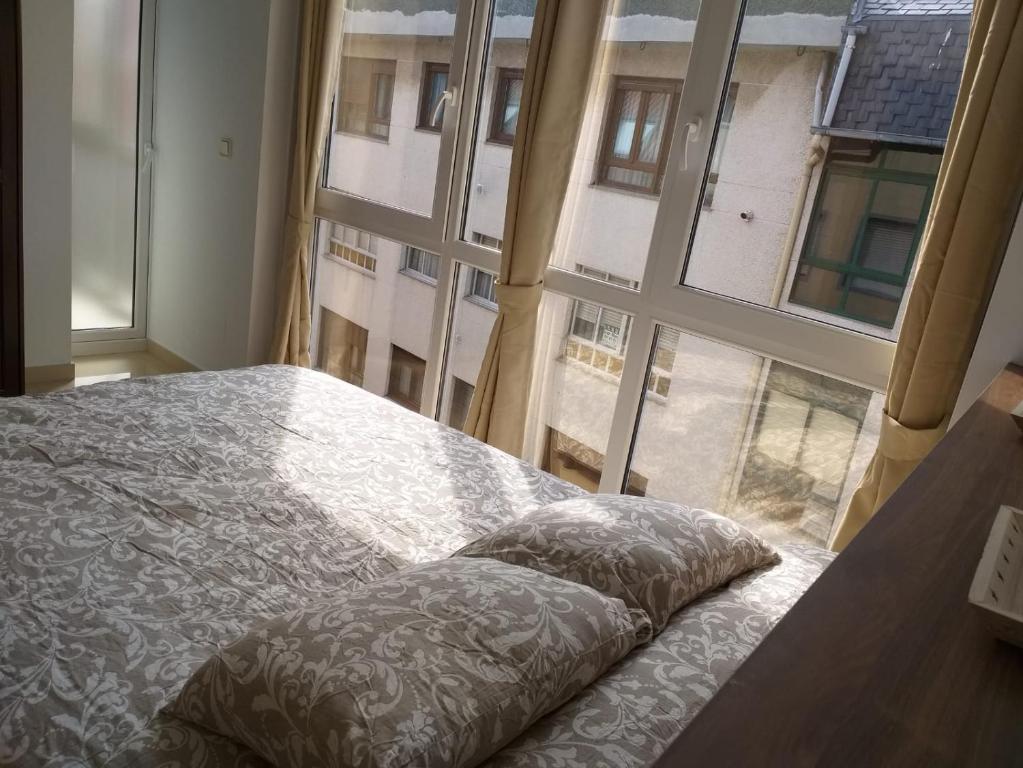 a bedroom with a bed and a large window at Apartamento en Ribeira(centro) 4* planta in Ribeira