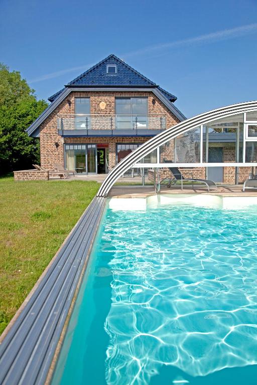 a house with a swimming pool in front of a house at Villa La Cigale in Boltenhagen