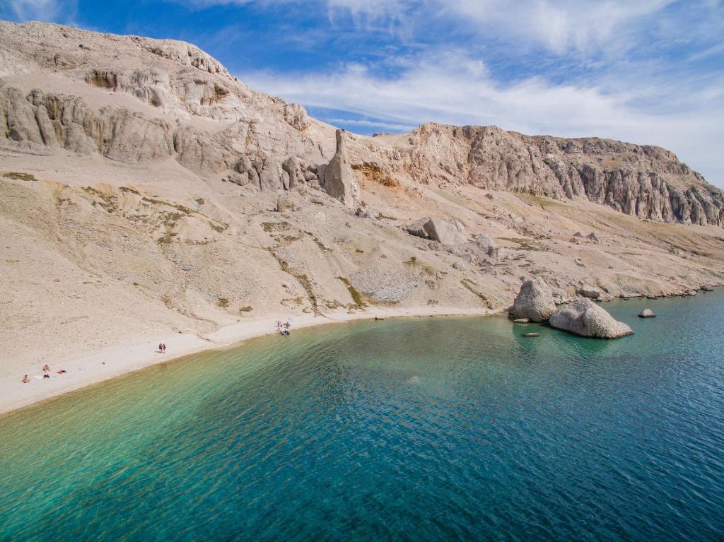 an aerial view of a beach next to a mountain at Apartments Niko Metajna, island Pag in Metajna