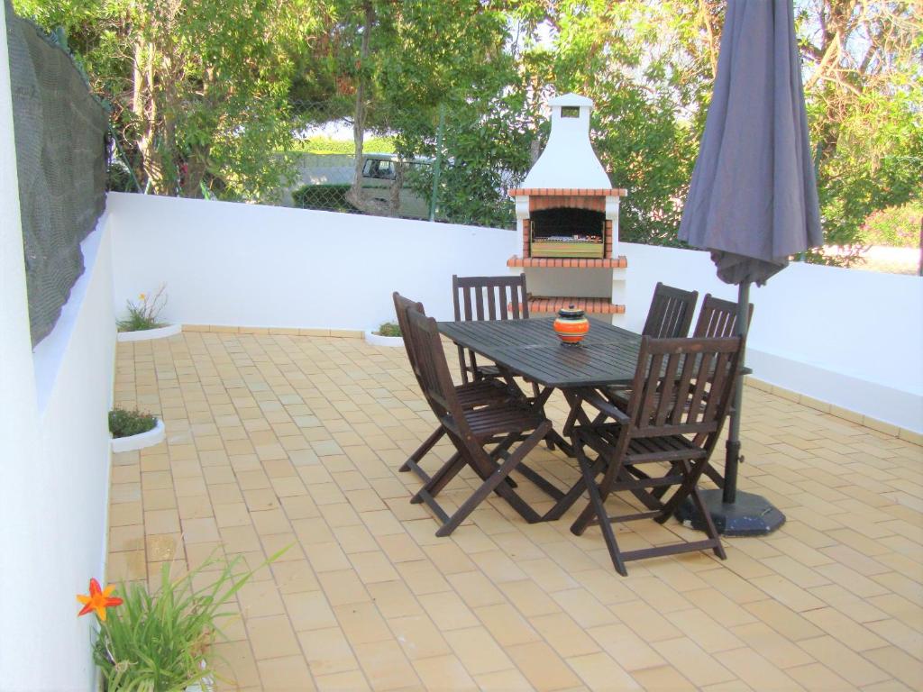 un patio con mesa, sillas y parrilla en Belinha Guest House, en Luz