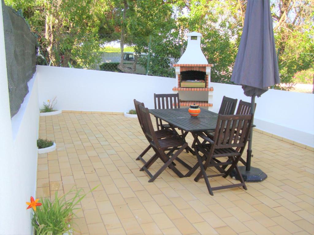 a patio with a table and chairs and a grill at Belinha Guest House in Luz