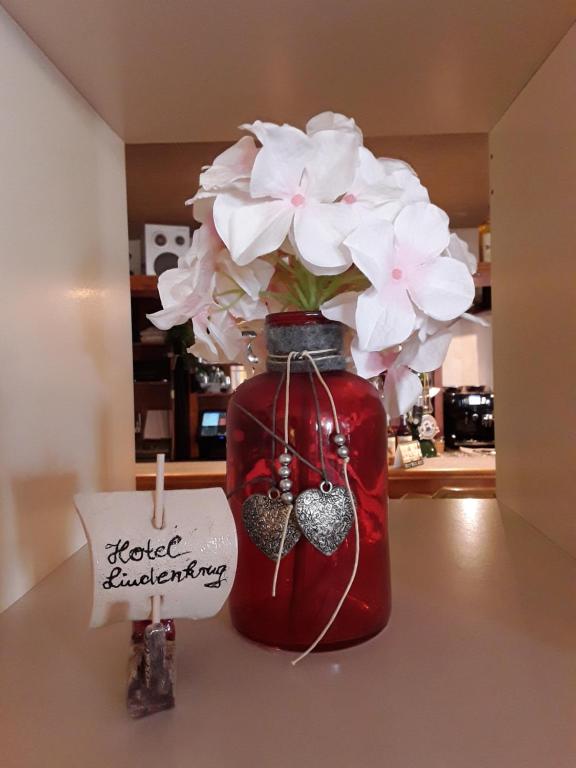 a red vase with white flowers in it with a sign at Gasthof Lindenkrug in Broderstorf