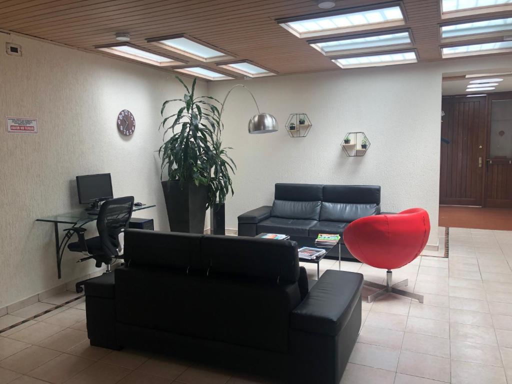 a living room with a couch and a red chair at Apartamentos Percales in Bogotá