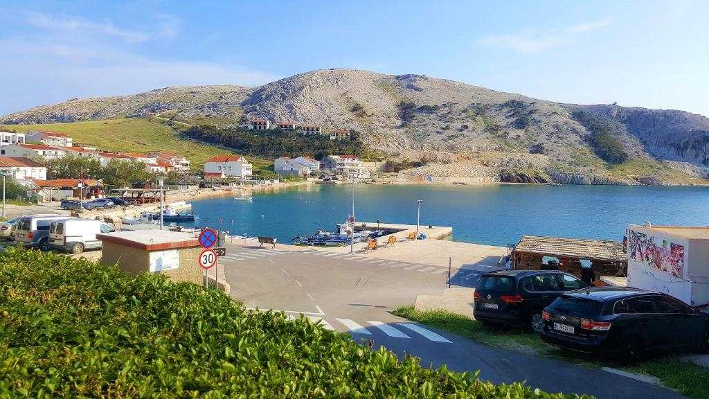 a parking lot next to a body of water with a mountain at Apartments Niko Metajna, island Pag in Metajna