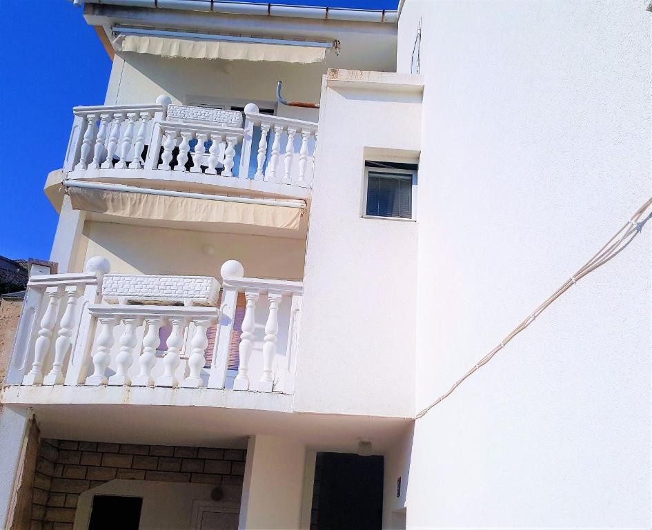 a white building with a balcony on the side of it at Apartments Niko Metajna, island Pag in Metajna
