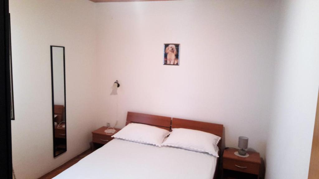a bedroom with a bed with two night stands and a mirror at Apartments Niko Metajna, island Pag in Metajna