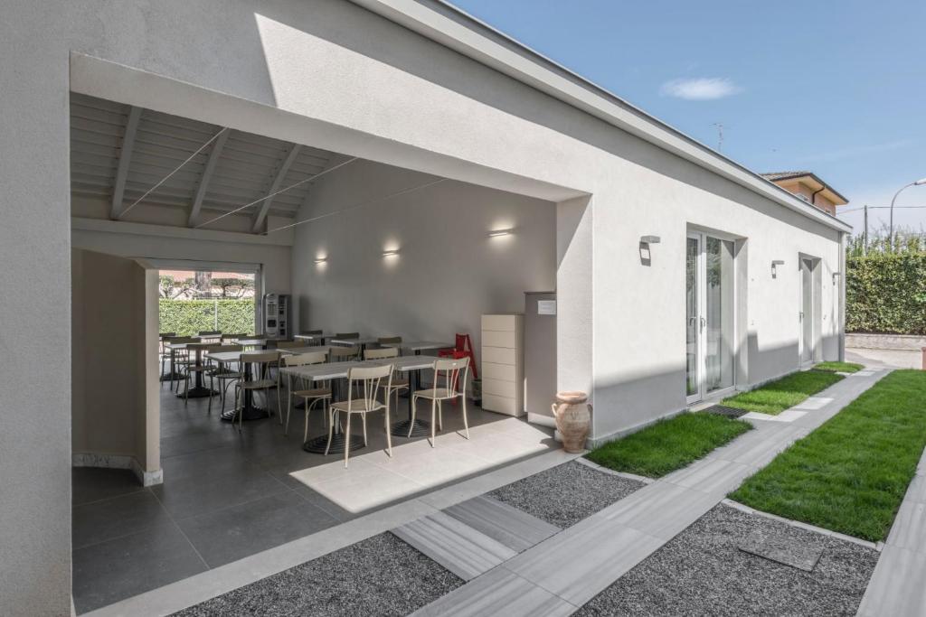 a white house with a patio with tables and chairs at Garda Guest House in Colà di Lazise